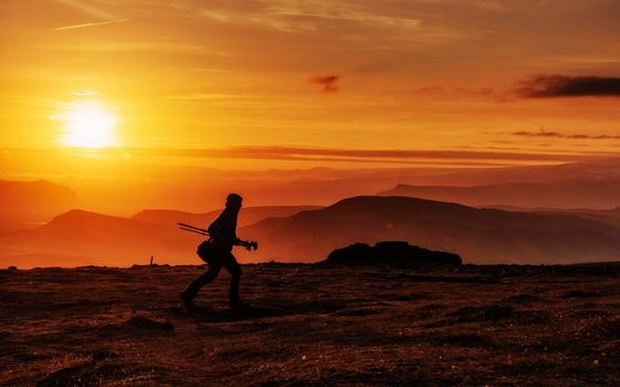 Happy man standing on a cliff at sunset.