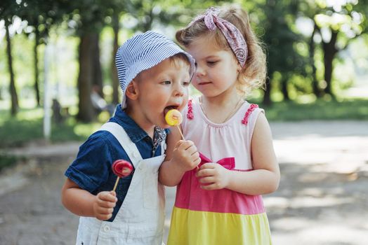 Happy children taste candy on a stick.