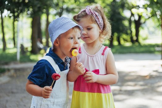 Happy children taste candy on a stick.