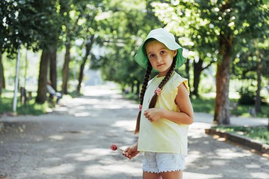 Funny child with candy lollipop, happy little girl eating big sugar lollipop, kid eat sweets.