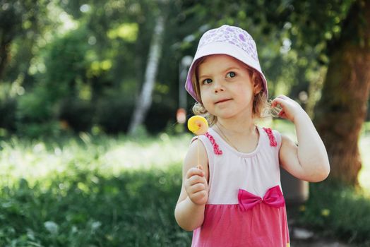 Funny child with candy lollipop, happy little girl eating big sugar lollipop, kid eat sweets.