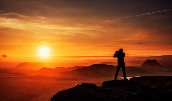 Happy man standing on a cliff at sunset.