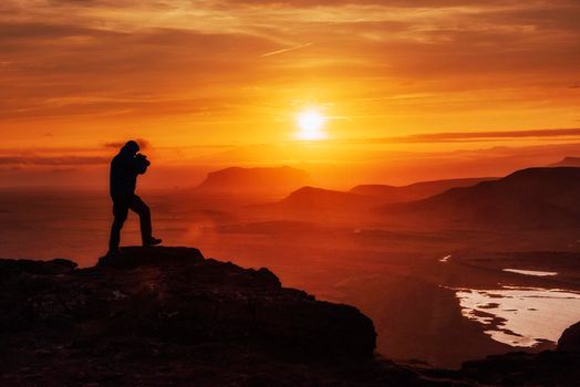 Happy man standing on a cliff at sunset.