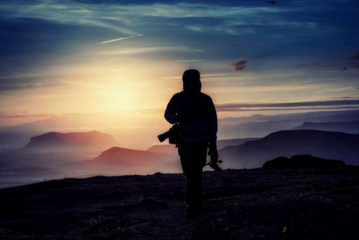 Happy man standing on a cliff at sunset.