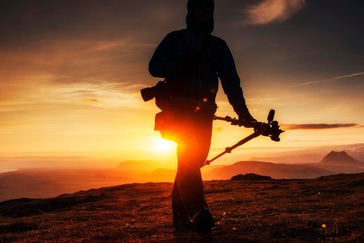 Happy man standing on a cliff at sunset.