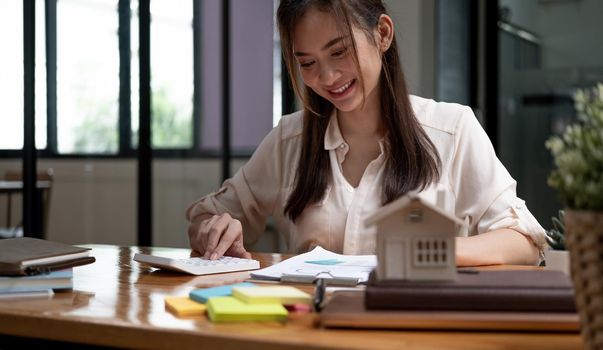 Businesswoman doing finances and calculate about cost to real estate investment and in other, tax system. Business Financing Accounting Banking Concept.