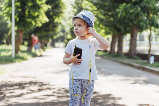 Cute girl listening to music with headphones outdoors.