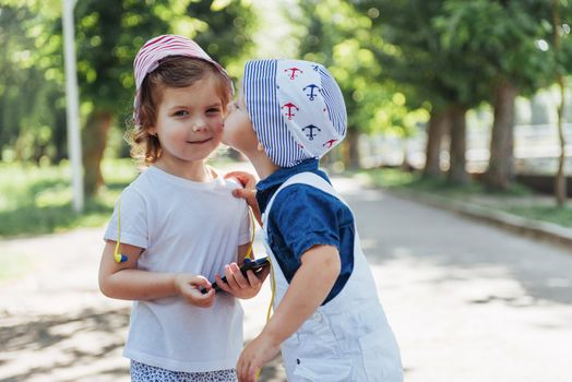 Cute girl and boy listening to music through headphones on the street.