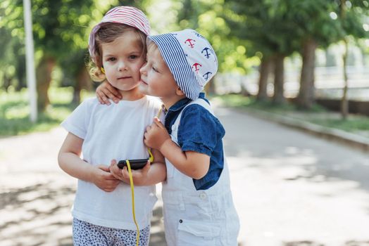 portrait of a little girl and her brother. Children playing outdoors on a sunny summer day. Family holidays.