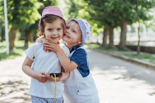 portrait of a little girl and her brother. Children playing outdoors on a sunny summer day. Family holidays.