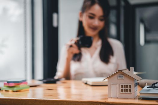 Real estate woman with house model on working desk for investment to buying property.