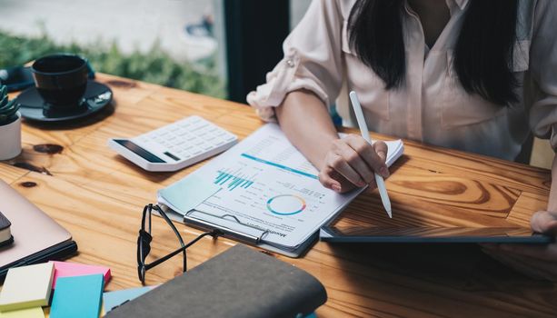 Close up Accounting woman using digital tablet with pen stylus on working space, business financial concept.