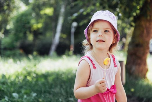 Funny child with candy lollipop, happy little girl eating big sugar lollipop, kid eat sweets.