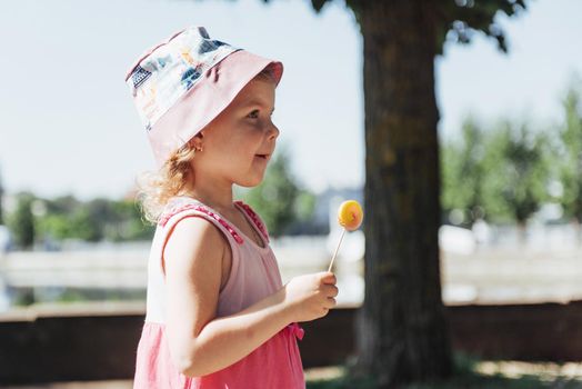 Funny child with candy lollipop, happy little girl eating big sugar lollipop, kid eat sweets.