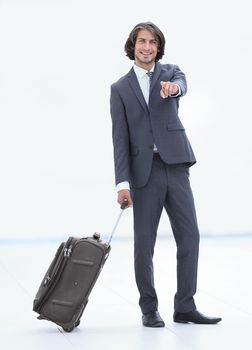 in full growth. businessman with travel suitcase pointing forward. photo with copy space.