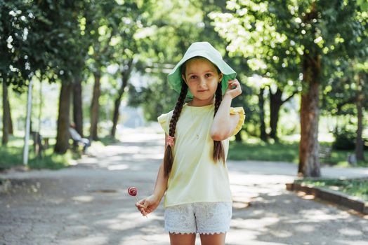 Funny child with candy lollipop, happy little girl eating big sugar lollipop, kid eat sweets.