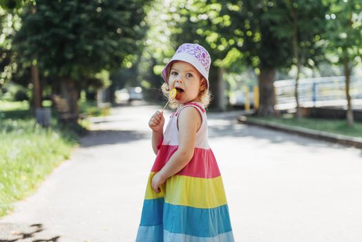 Funny child with candy lollipop, happy little girl eating big sugar lollipop, kid eat sweets.