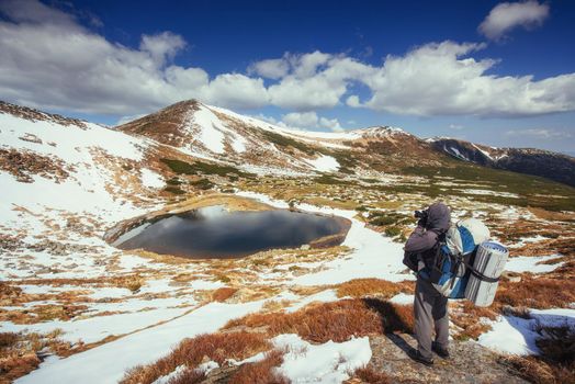 Mountain Lake. Sky reflected in the water. A tourist looks at the landscape. Spring landscape. Carpathian Mountains, Ukraine