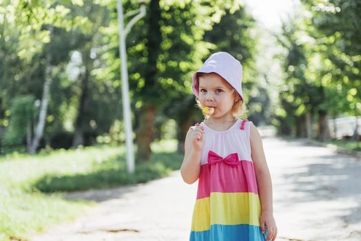 Funny child with candy lollipop, happy little girl eating big sugar lollipop, kid eat sweets.