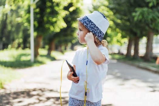 Cute girl listening to music with headphones outdoors.