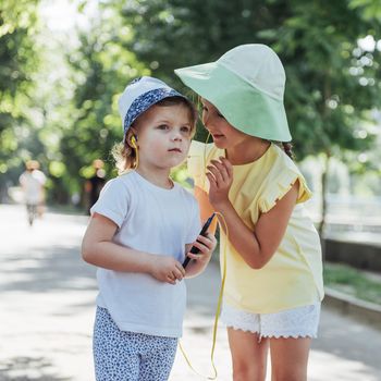 Happy girl with headphones to share music from your smartphone on street