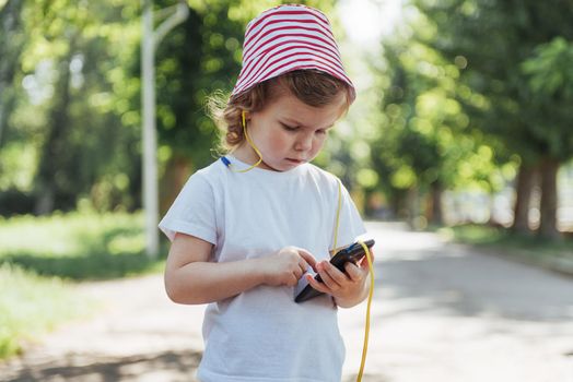 Cute girl listening to music with headphones outdoors.
