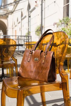 close-up photo of yellow leather bag on a stylish plastic chair. Outdoor photo