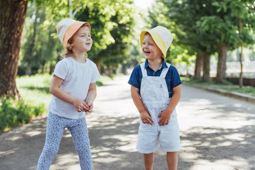 portrait of a little girl and her brother. Children playing outdoors on a sunny summer day. Family holidays.