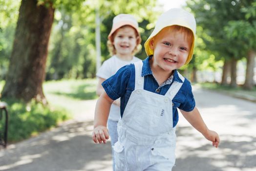 portrait of a little girl and her brother. Children playing outdoors on a sunny summer day. Family holidays.