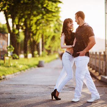 young couple dancing tango on the quay of the river at night