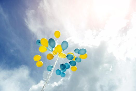 bouquet of blue and yellow balloons in the sky.