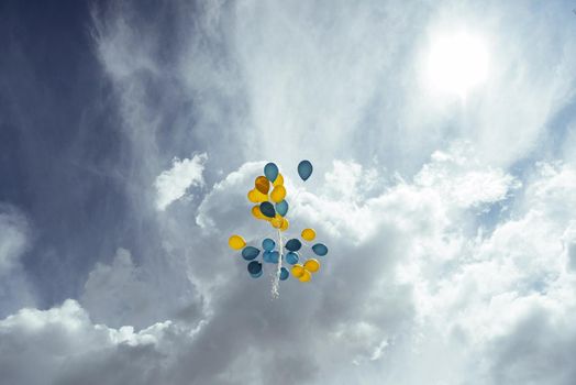 bouquet of blue and yellow balloons in the sky.