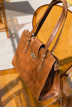 close-up photo of yellow leather bag on a stylish plastic chair. Outdoor photo