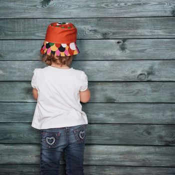 Stylish teenage girl leaning against a wall and looking at the camera