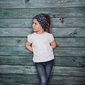 Stylish teenage girl leaning against a wall and looking at the camera