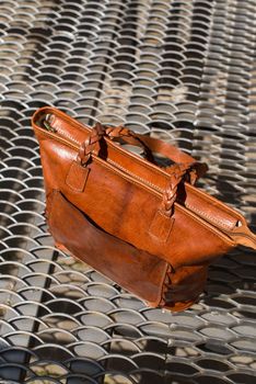 close-up photo of orange leather bag on a metal texture background. outdoor photo