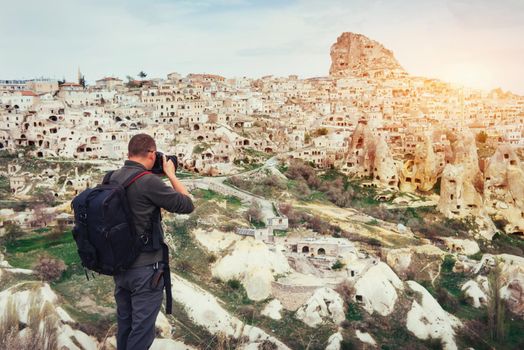 man photographs the ancient city and the castle Uchhysar dug from the mountains. Cappadocia, Turkey