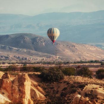 Colorful hot air balloons flying over Red valley at Cappadocia, Anatolia, Turkey. Volcanic mountains in Goreme national park.