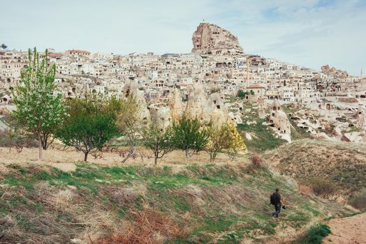 man photographs the ancient city and the castle Uchhysar dug from the mountains. Cappadocia, Turkey