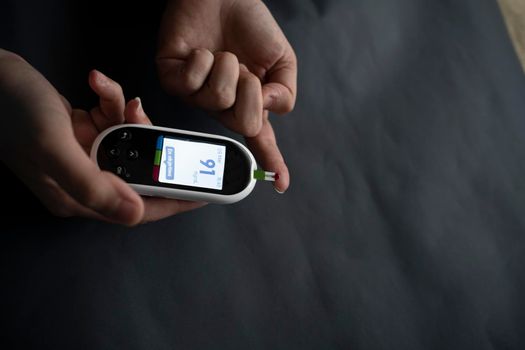 Woman with glucometer checking blood sugar level at home. Diabetes, health care concept. Young woman using digital glucometer at home. control diabetes