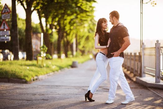 young couple dancing tango on the quay of the river at night