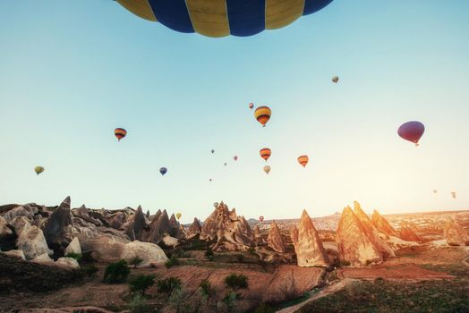 Colorful hot air balloons flying over Red valley at Cappadocia, Anatolia, Turkey. Volcanic mountains in Goreme national park.