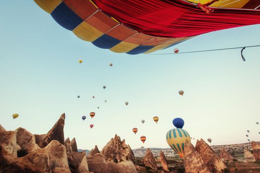 Colorful hot air balloons flying over Red valley at Cappadocia, Anatolia, Turkey. Volcanic mountains in Goreme national park.