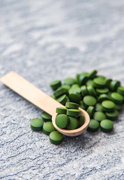 Green pills of chlorella and spirulina. Selective focus drink