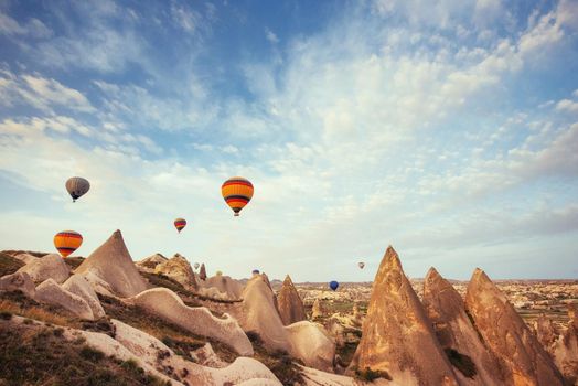 Hot air balloon flying over rock landscape at Cappadocia Turkey. Cappadocia with its valley, ravine, hills, located between the volcanic mountains in Goreme National Park.