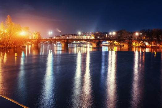 Scenic view of bridges on the Vltava river and of the historical center of Prague: buildings and landmarks of old town with red rooftops.