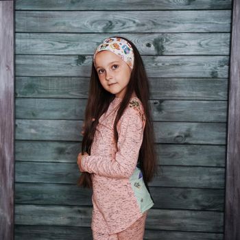 Stylish teenage girl leaning against a wall and looking at the camera