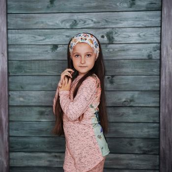 Stylish teenage girl leaning against a wall and looking at the camera