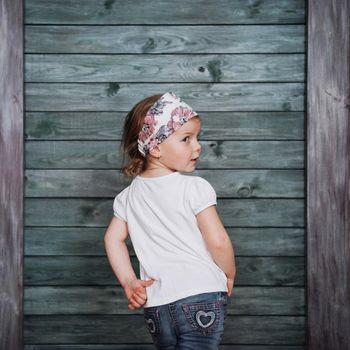 Stylish teenage girl leaning against a wall and looking at the camera