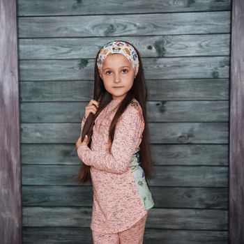 Stylish teenage girl leaning against a wall and looking at the camera